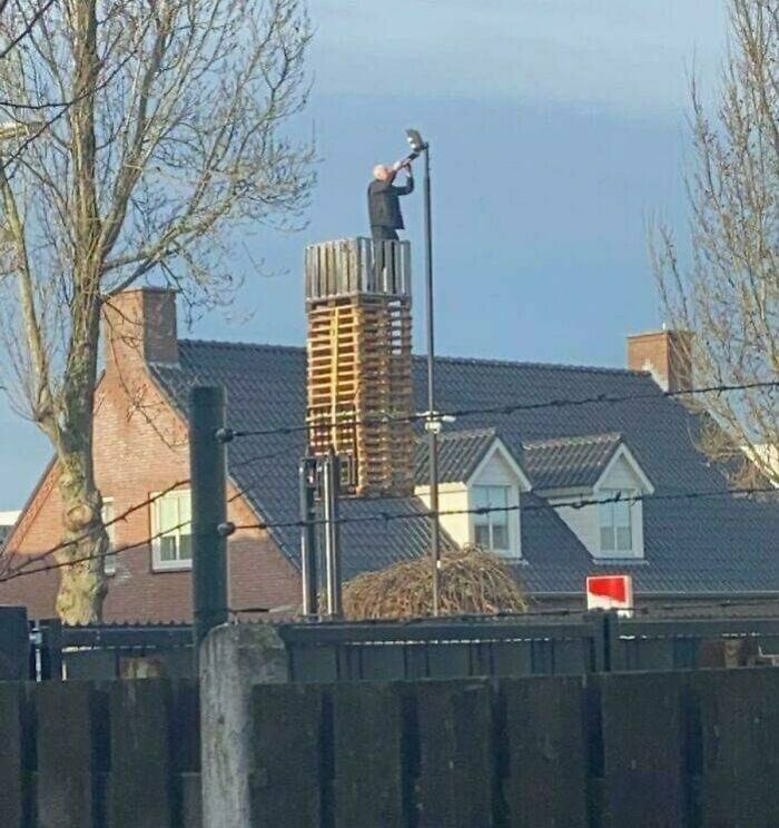 Just A Man On A Stack Of Pallets Raised By A Forklift Changing The Bulb On A Street Light
