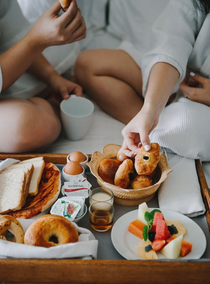 Two people eating food on bed 