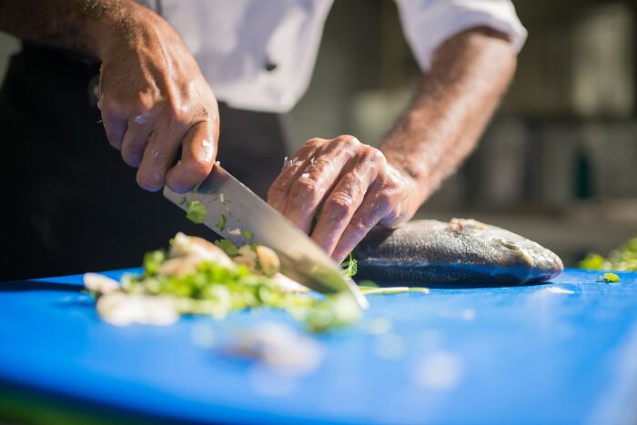 Kitchen Chef Preparing Vegetables And Cutting Fish 