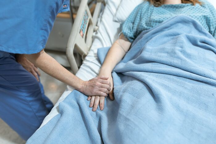 Patient Lying In Hospitals Bed And Doctor Is Holding Her Hand 