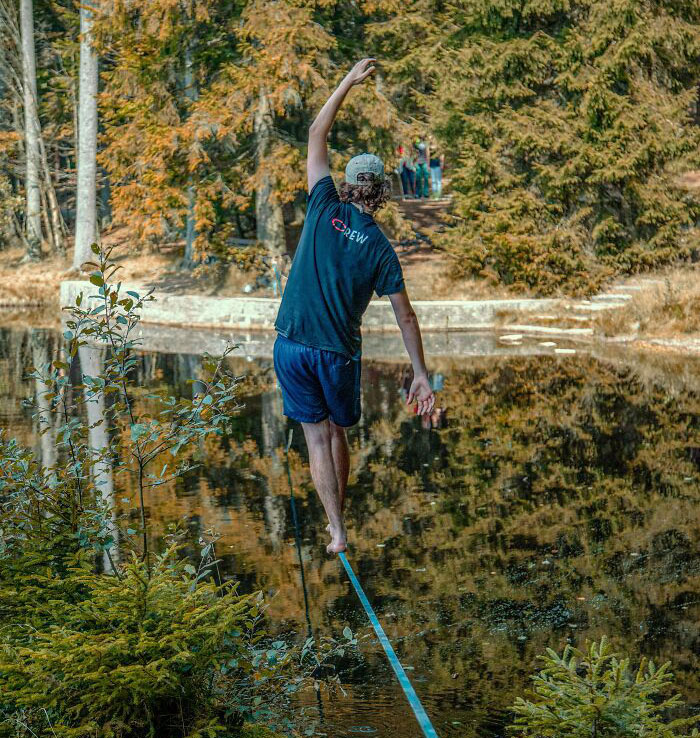 Man Walking And Balancing On A Tight Rope Above A Lake 