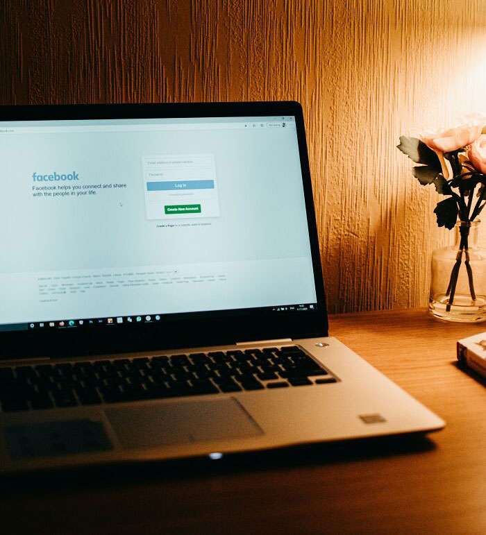 Person Using Facebook On Laptop In A Cozy Room 