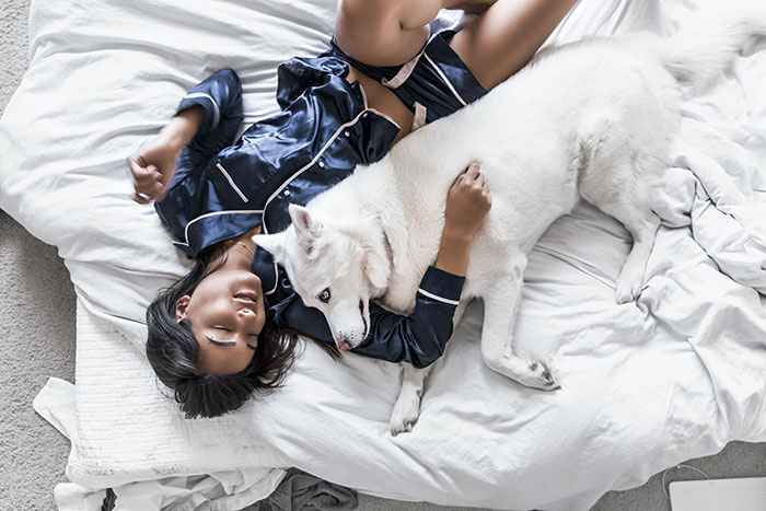 Woman lying in the bed with white dog