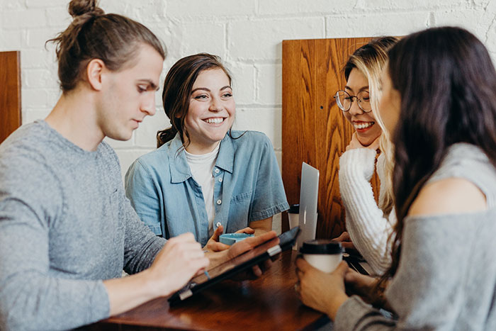 Friends looking at phones and computers and talking