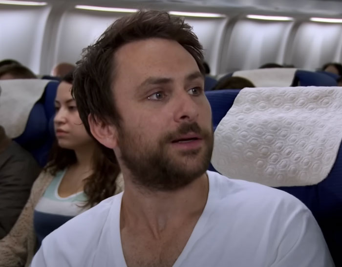 Charlie Kelly wearing white t-shirt on a plane 