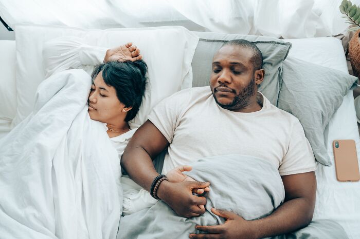 Couple Laying In Bed While Holding Hands 