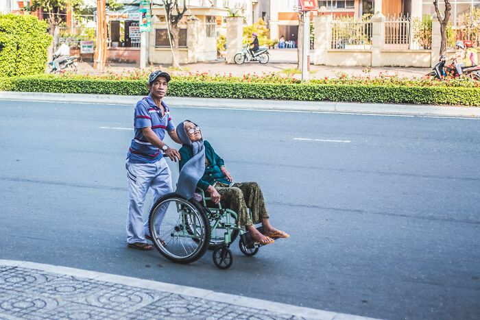 Man Helping A Woman In Wheelchair 