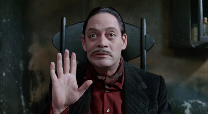 Gomez Addams holding hand and sitting from The Addams Family