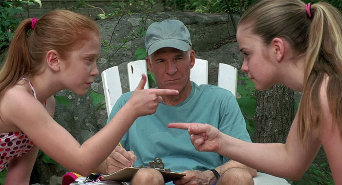 Tom Baker sitting and looking at girls that points at each other from Cheaper by the Dozen