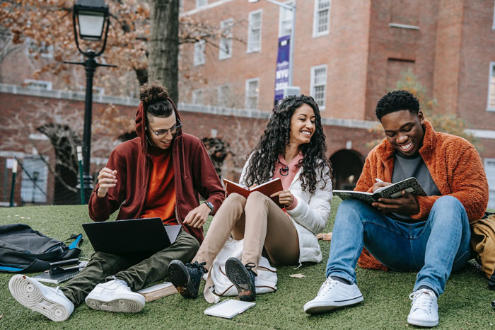 three persons sitting on the ground with copybooks