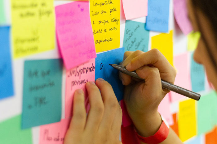 a person writing something on pink sticky notes