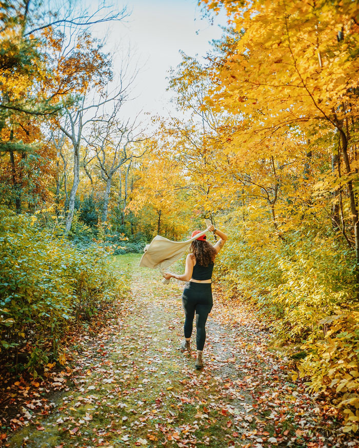 a woman walking in the forest with yellow trees