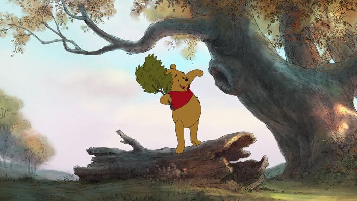 Winnie The Pooh standing on a log in the forest and holding tree branch in his hands