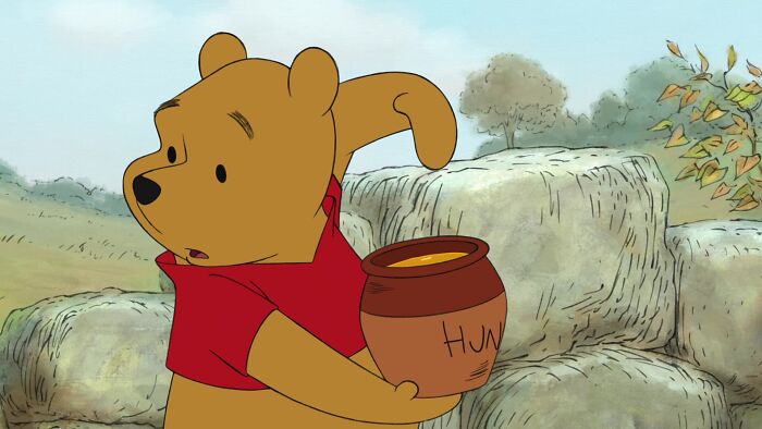 Winnie the Pooh holding a a pot of honey