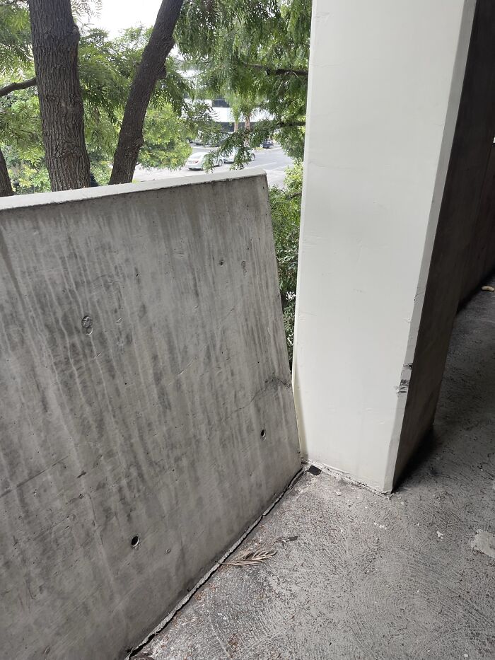 This Parking Garage Showcases An Extremely Concerning Issue With Its Vehicle Barrier Wall, Which Is Visibly Disconnected From The Structure And Leaning Over With A Noticeable Tilt