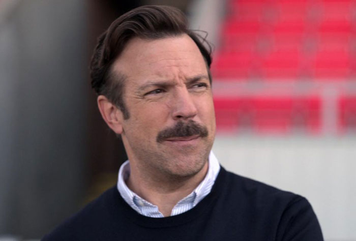 Ted Lasso wearing blue sweater and white shirt