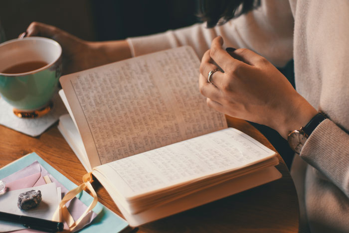 a person reading the notes in the notebook with a cup of coffee