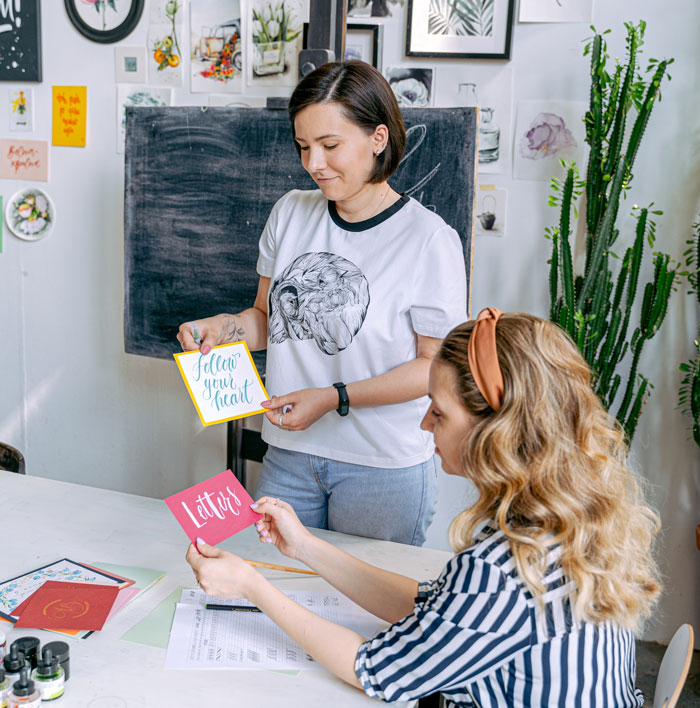 women holding cards with a handwritten lettering