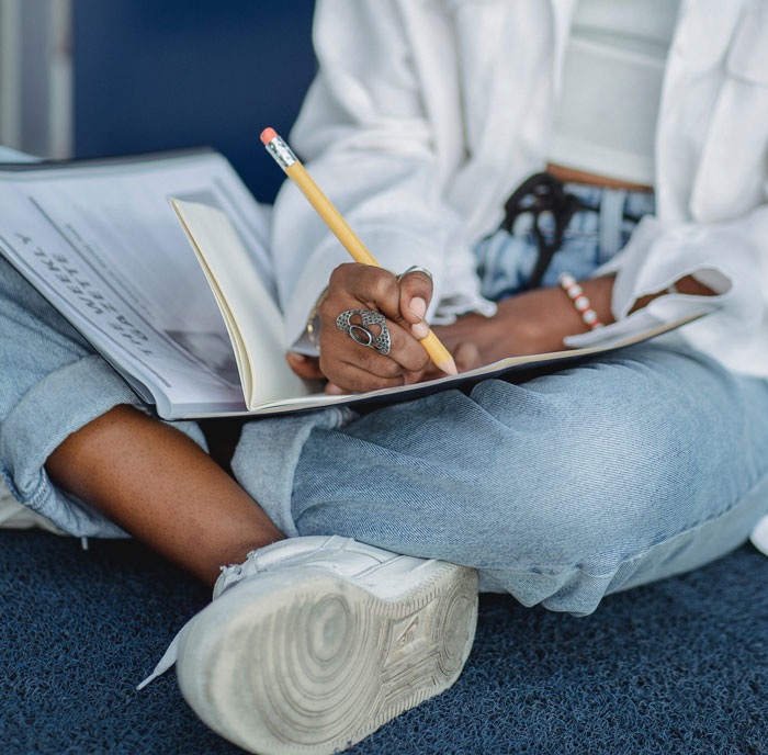 a woman writing something with a pencil in the notebook