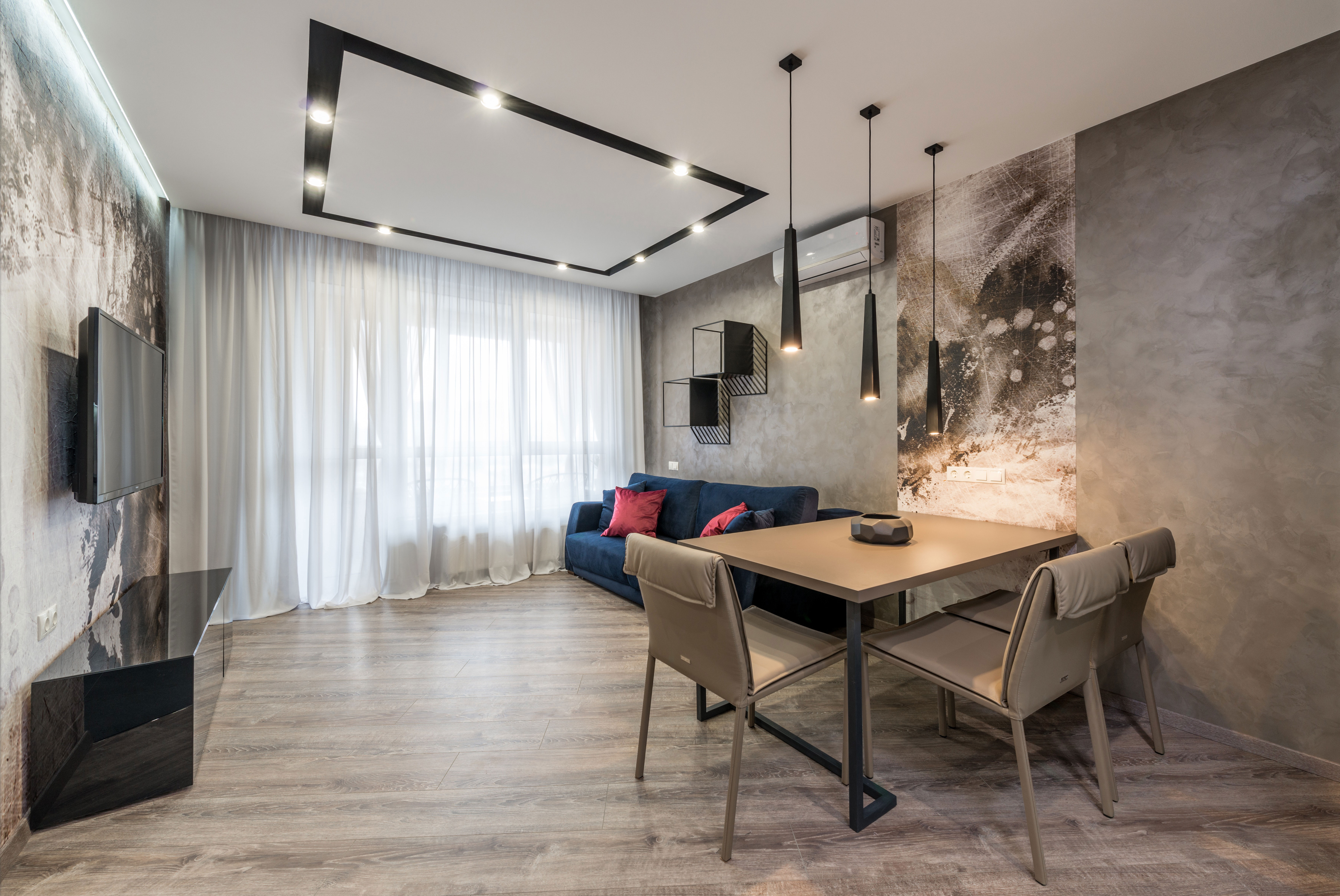 Tv hanging on wall in front of soft couch and dining table 