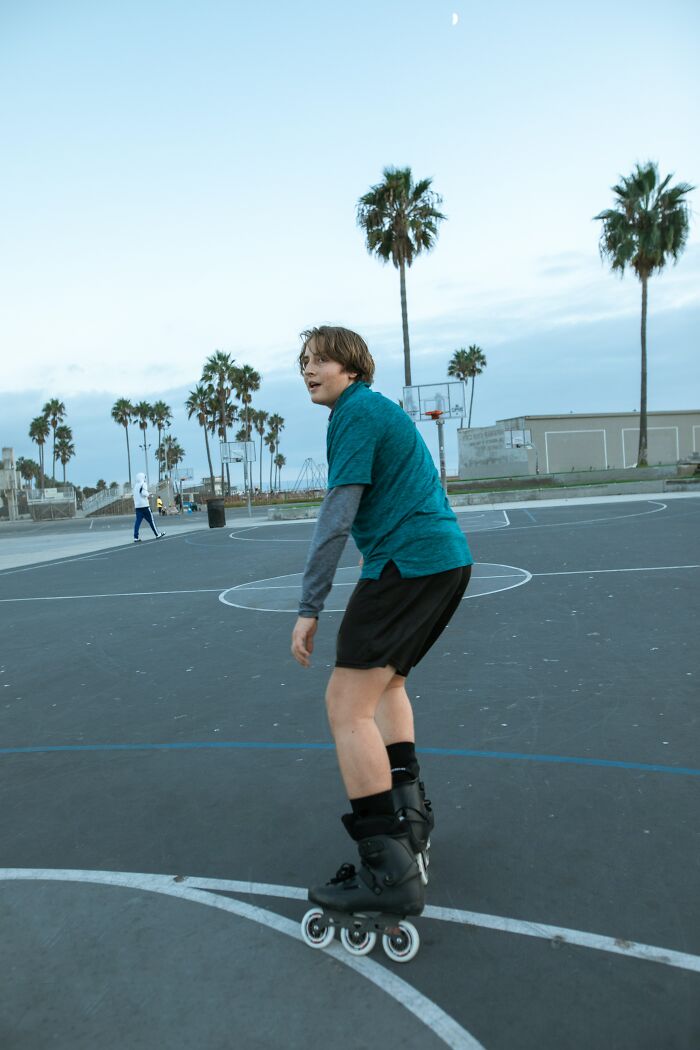 A Young Man Using Rollerblades in a Basketball Court