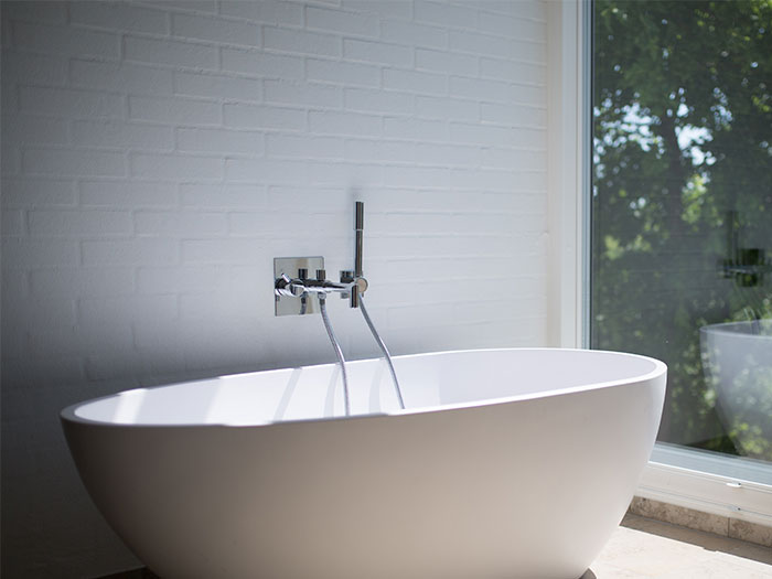White ceramic bathtub beside clear glass wall