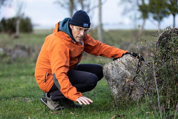 a man in an orange jacket leans on a rocks