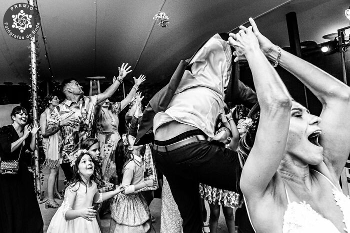 Guests eagerly reach for the bouquet in an incredible wedding photo selected by Premios FdB.