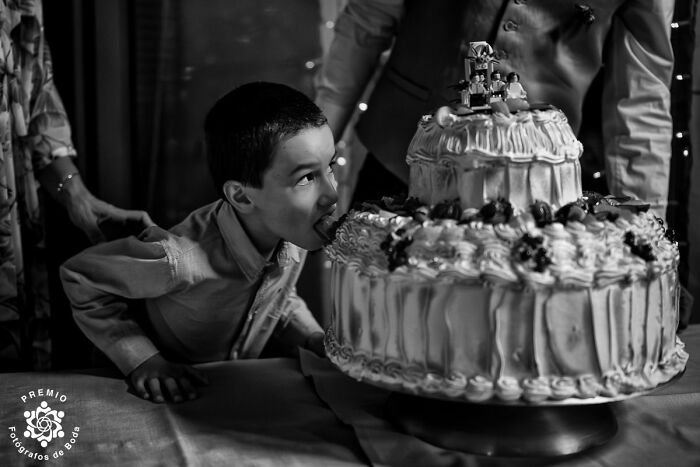 Child playfully eating a wedding cake during a celebration, captured among the incredible wedding photos of 2024.