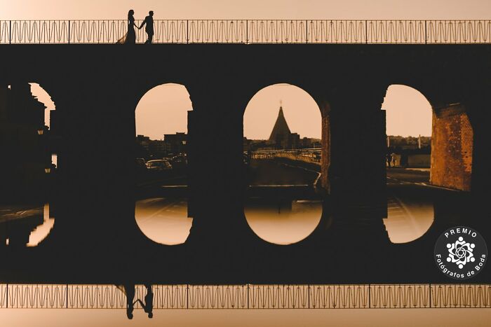 Silhouetted couple on a bridge during sunset, capturing an incredible wedding photo.