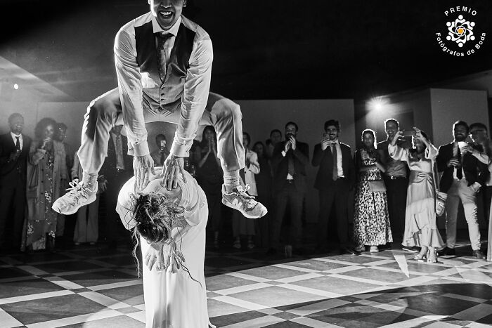 An incredible wedding photo with a dynamic dance move, featuring a groom jumping over the bride's back.