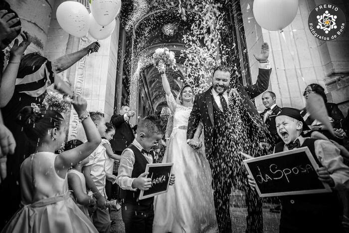 Incredible wedding photo of couple celebrating with guests throwing rice, selected by Premios FdB 2024.