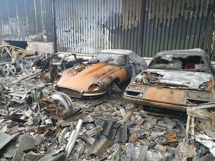 Damaged vintage cars in a burnt garage, showcasing expensive unfortunate incidents.