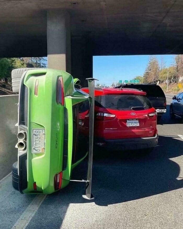 Green sports car flipped onto its side next to a red SUV, likely an expensive incident.