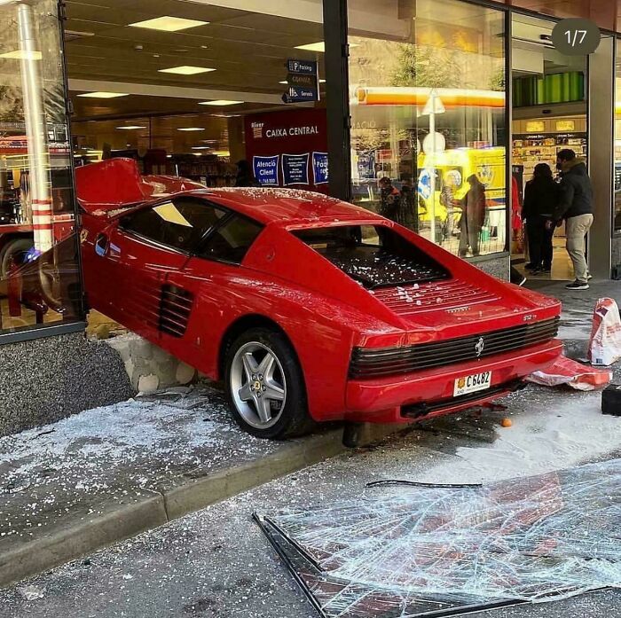 Red sports car crashes into storefront, causing significant damage and looking expensive to repair.