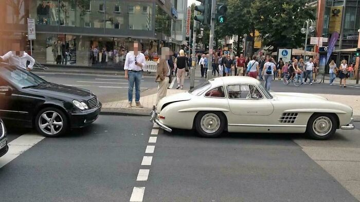 Expensive car accident at intersection, vintage white sports car rear-ended by black sedan.