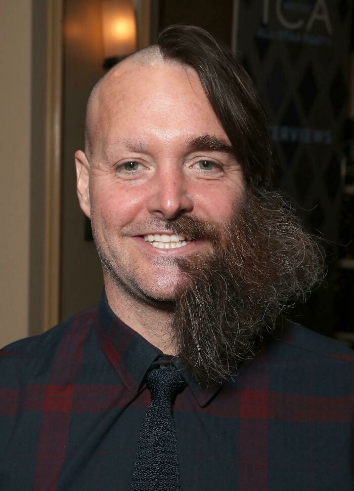 Man with an unusual hairstyle, half shaved head and half long beard, demonstrating a tragic hair accident.