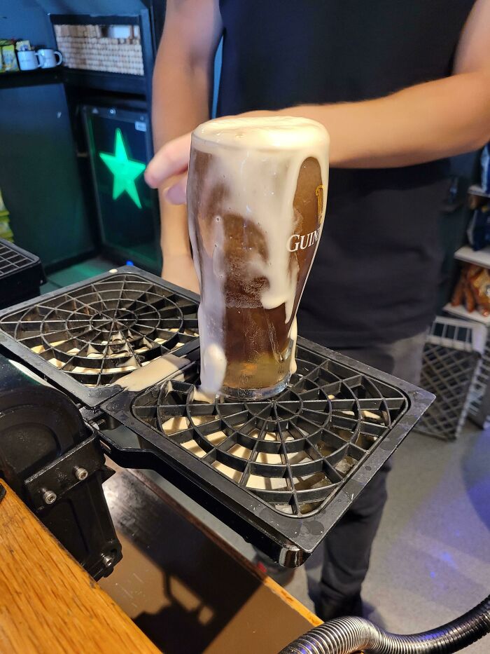 Foamy pint of Guinness on a bar counter, capturing uniquely British pub humor.