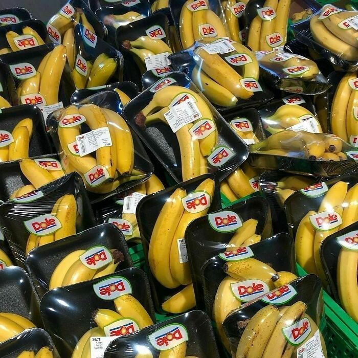 Bananas wrapped excessively in plastic packaging, highlighting poor product packaging choices.