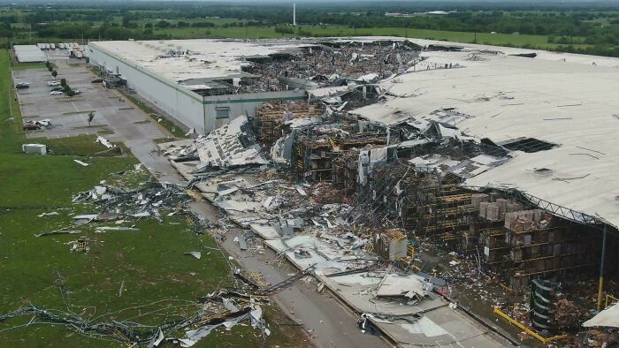 Damaged warehouse with collapsed roof, debris scattered; an unfortunate incident likely costing a fortune.