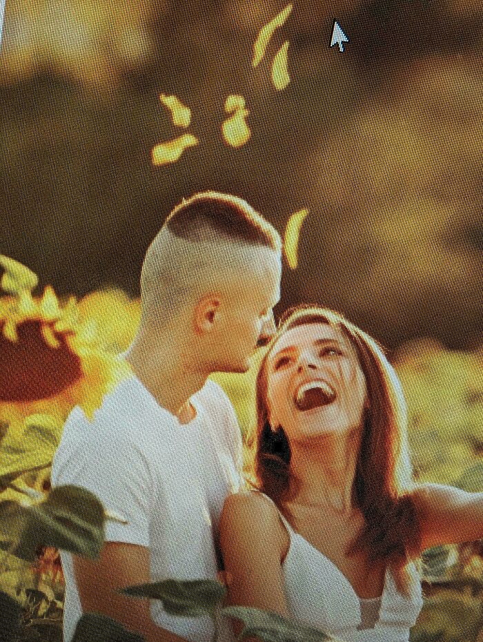 A couple embraces in a field, the man with a uniquely shaved hairstyle, capturing a lighthearted hair accident moment.