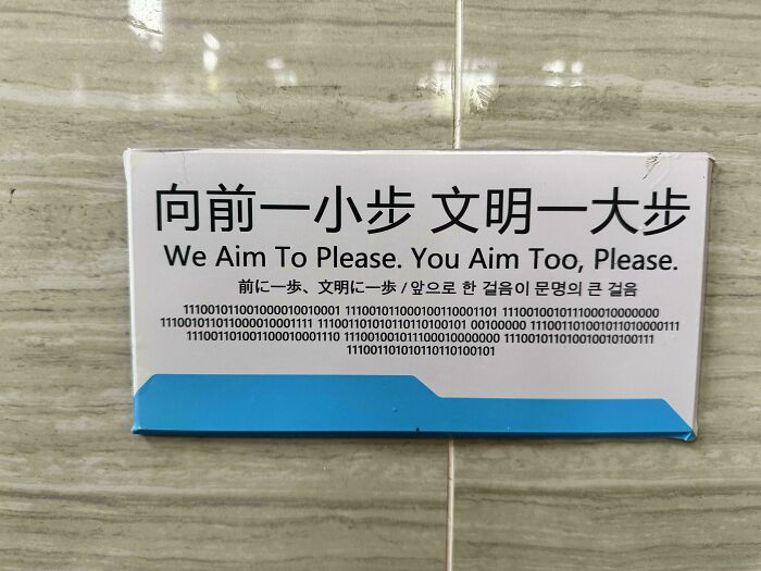 A Sign Over A Urinal In Chinese, English, Japanese, Korean And Binary