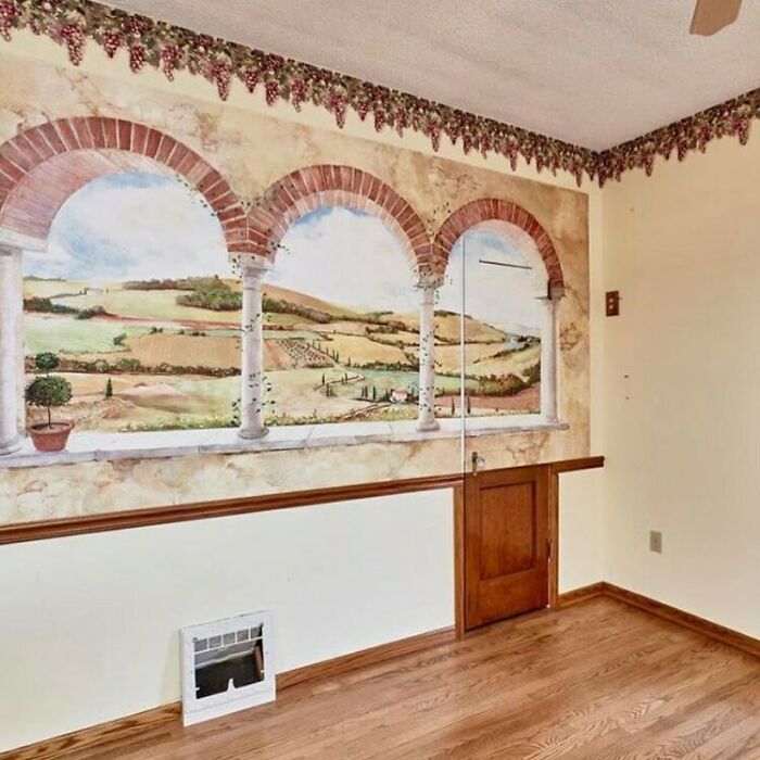 Interior design disaster featuring a misleading mural with arches and scenery, clashing with door placement.