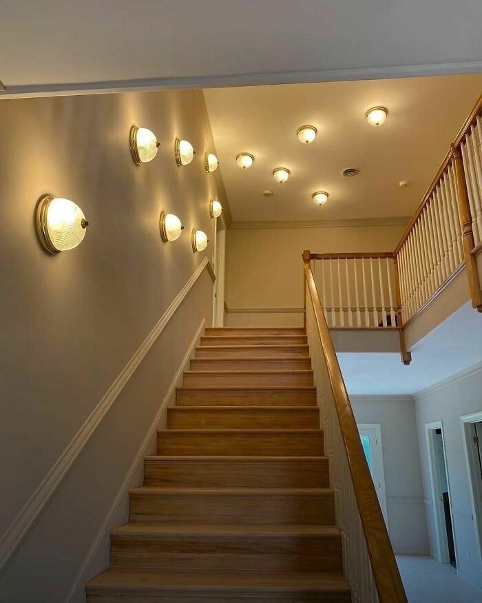 Staircase with excessive ceiling and wall lights creates a design disaster needing to be shamed.