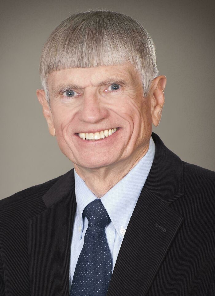 Smiling man in formal attire with a unique haircut, showcasing a humorous hair accident.