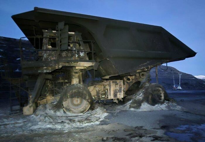 A large dump truck appears damaged, with melted tires, possibly indicating an expensive unfortunate incident.