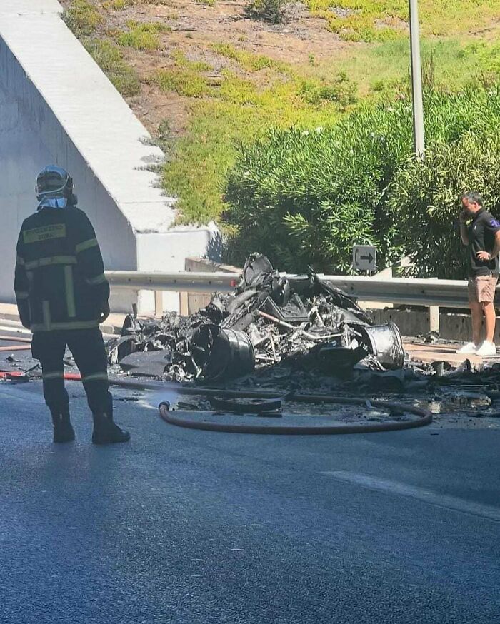 Firefighter observing expensive car wreckage on highway; likely costly incident.