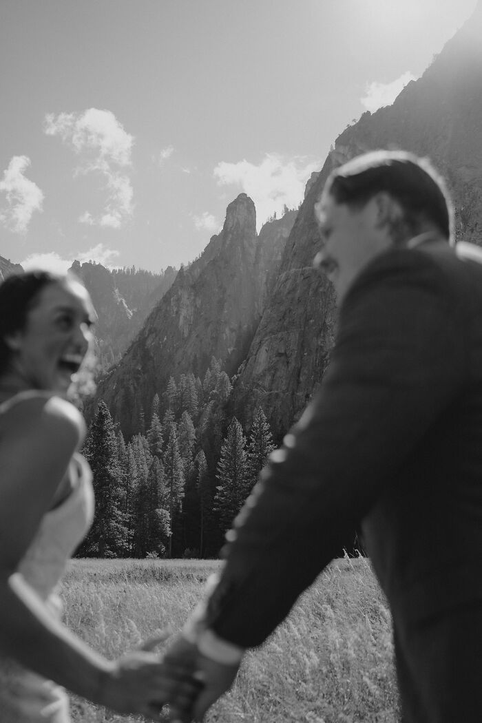 Couple holding hands and smiling in front of a mountain backdrop, showcasing top destination wedding photo of 2024.