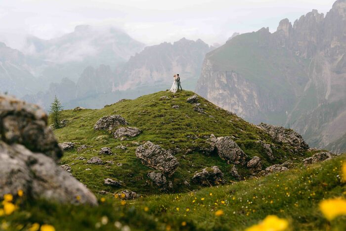 Couple embraces on a scenic mountaintop, capturing a stunning destination wedding moment.