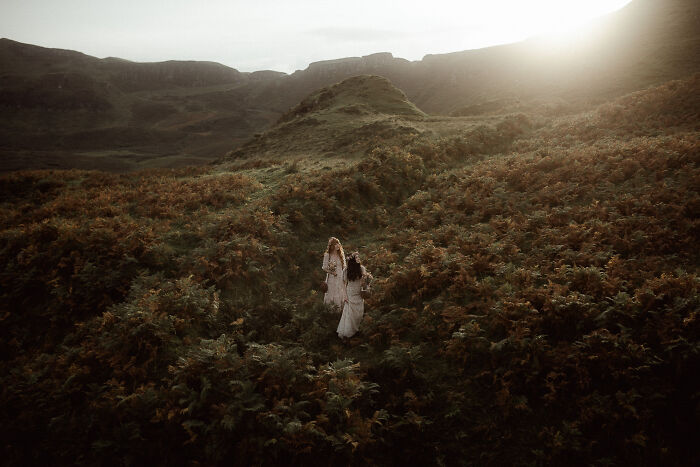 Couple in wedding attire embracing in a scenic field during sunset, capturing a top 2024 destination wedding photo.